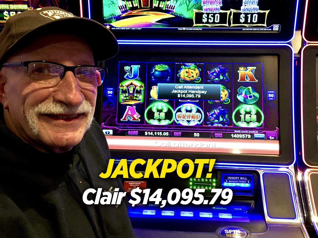 A man in black hat and glasses standing next to slot machine.
