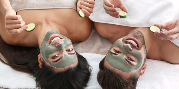 Two women with face masks on laying in bed