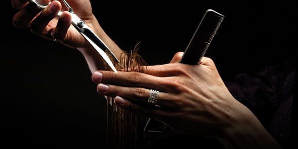 A person cutting their hair with scissors and comb.
