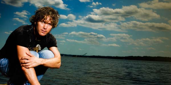 A man holding a frisbee in front of the water.