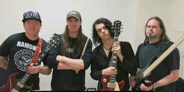 A group of people holding guitars in front of a wall.