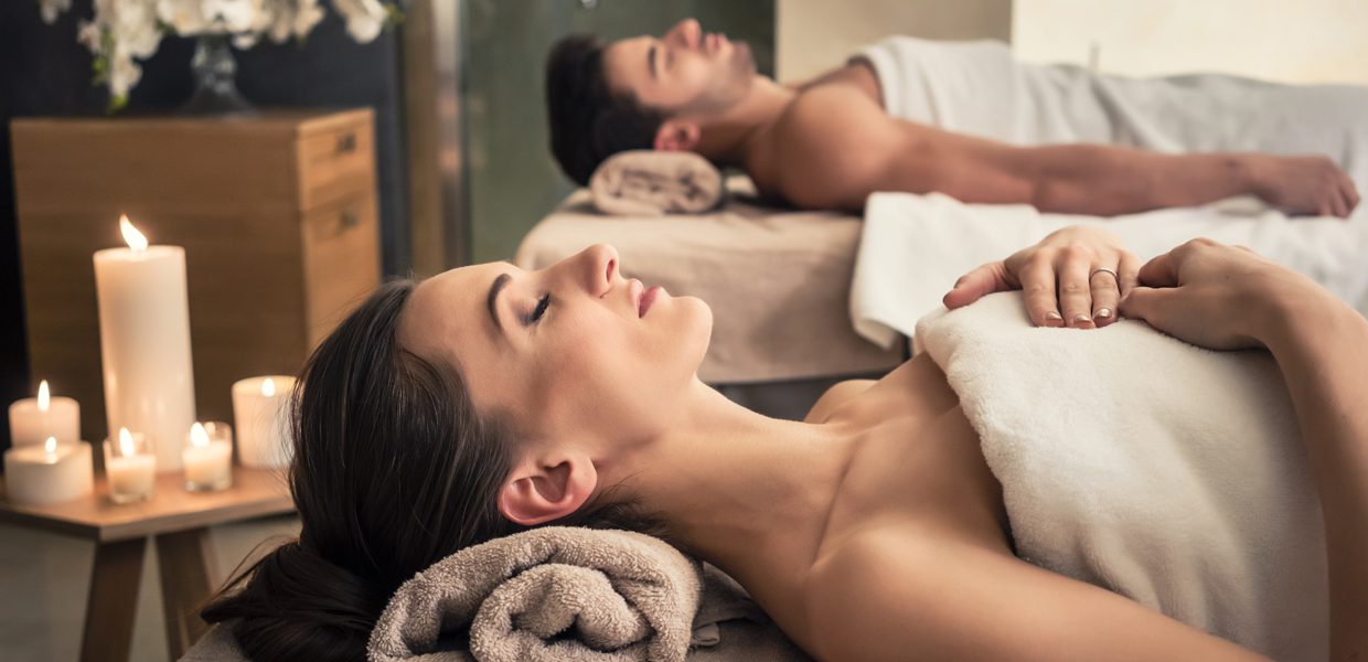 A man and woman laying on towels in a spa.