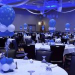 A room with tables and chairs, balloons in the shape of stars.