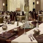 A table set up for an event with wine glasses and silverware.