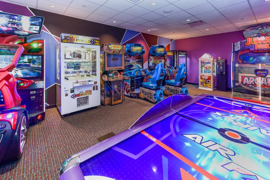 A room with several arcade machines and cars.