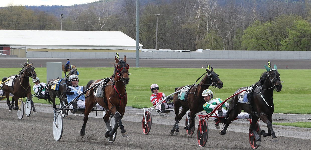 A group of men riding horses on top of asphalt.