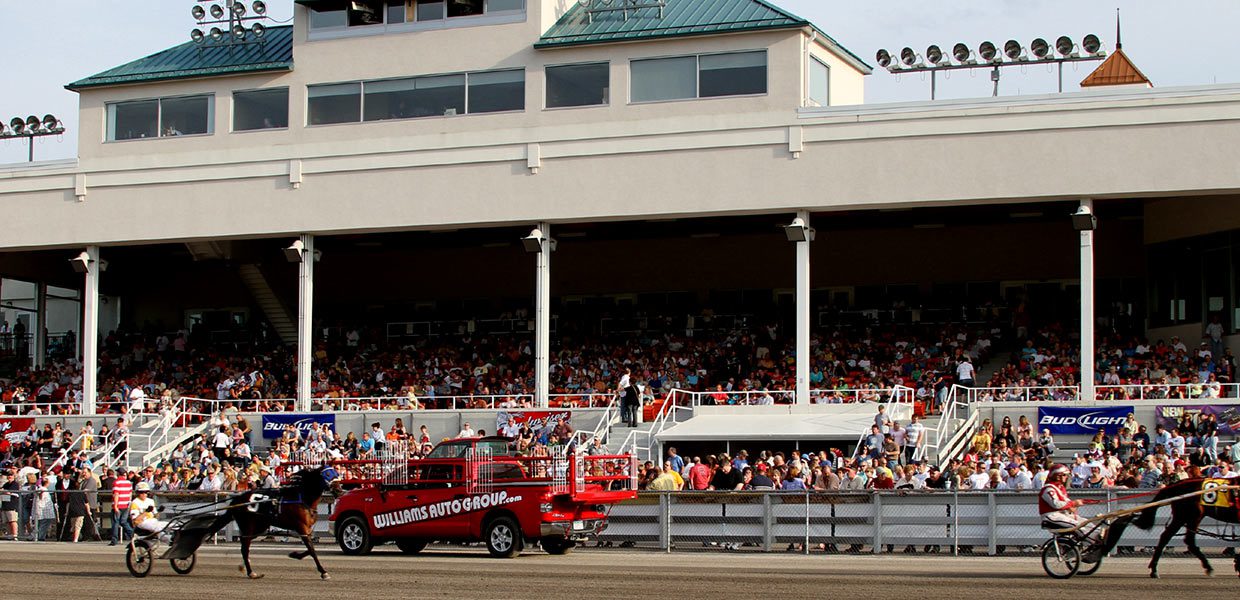 A red truck driving down the road in front of an audience.
