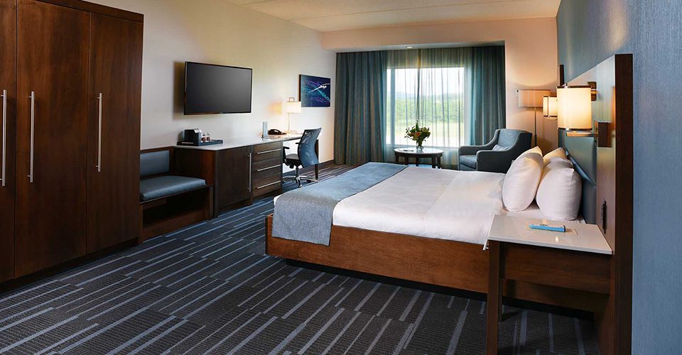 A hotel room with a bed, chair and television.