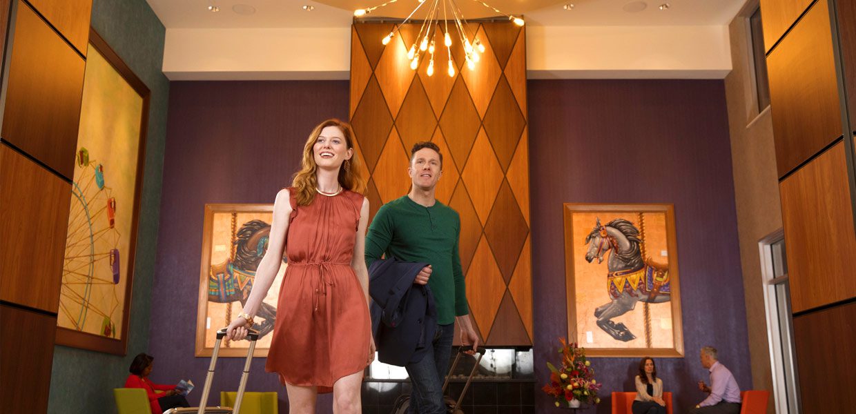 A man and woman walking in front of a diamond pattern wall.