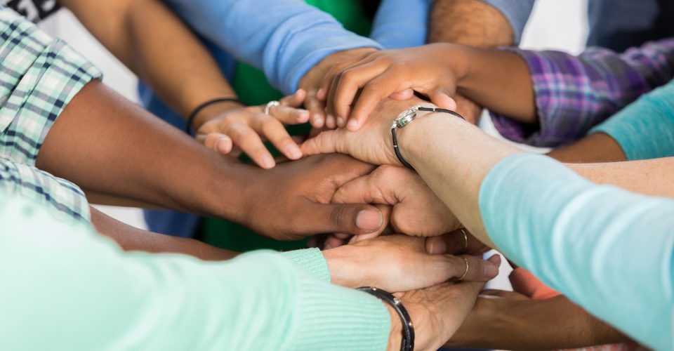 A group of people holding hands in the middle of a circle.