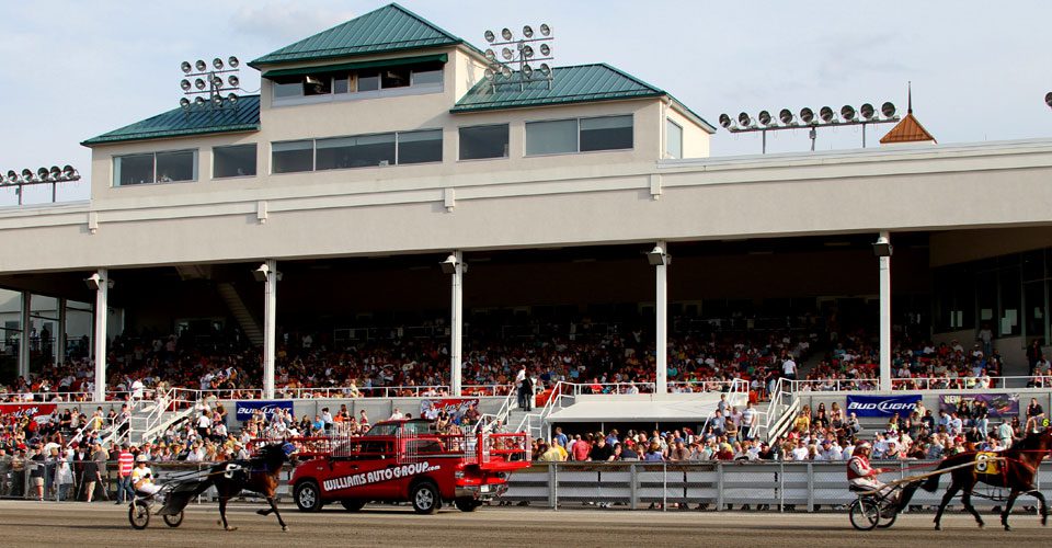 A red tow truck driving down the street in front of an audience.