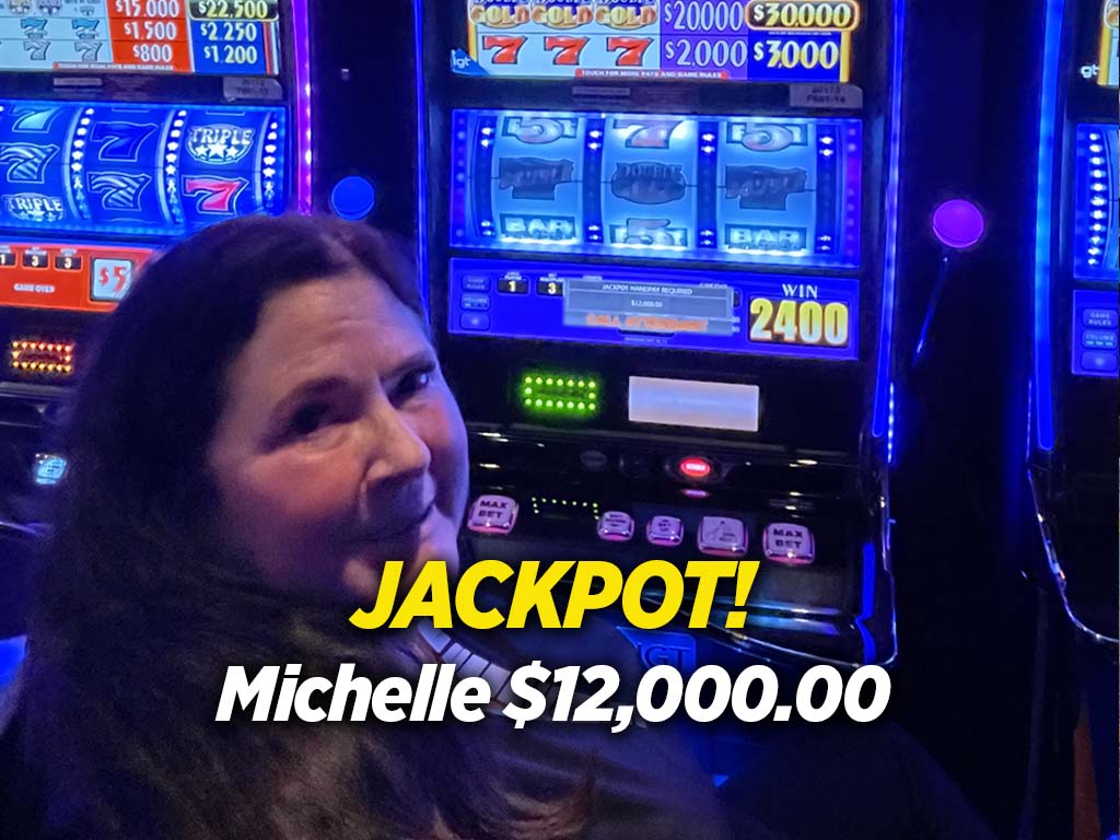 A woman is smiling in front of a slot machine.